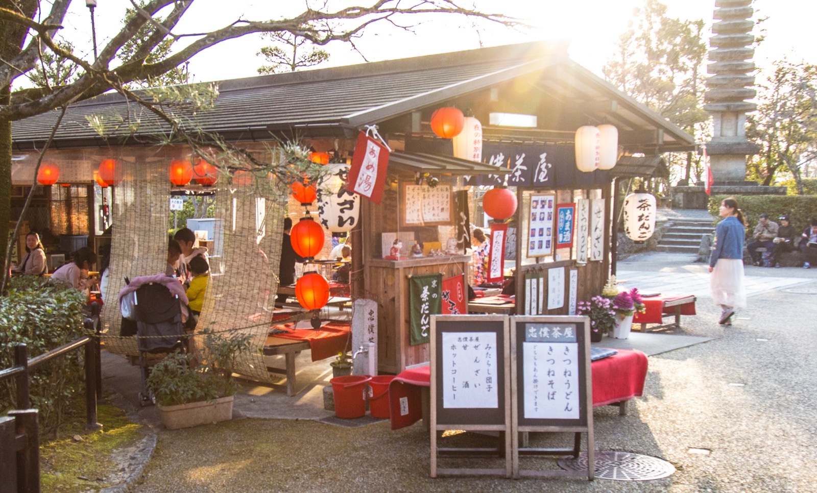 Chūboku Chaya with red lanterns, shop-name curtain and menu boards beside a stone tower.